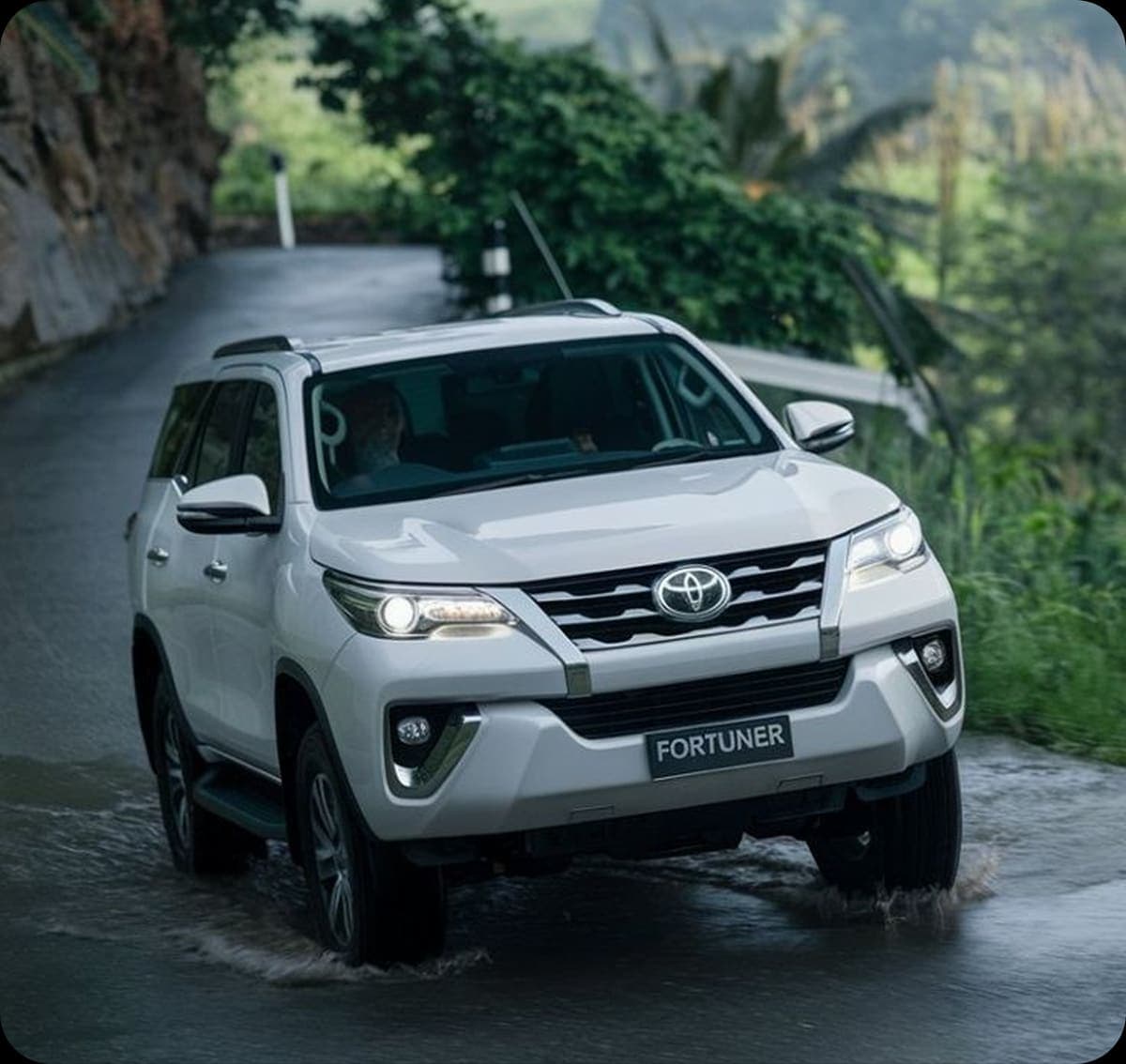 Toyota Fortuner on a forest road under a rock overhang